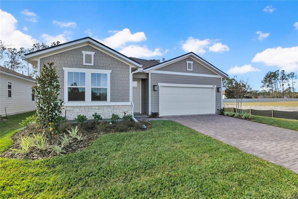 A single-story house with gray siding, stone accents, a two-car garage, and a paved driveway — 188 ENCLAVE AVENUE, PALM COAST, FL