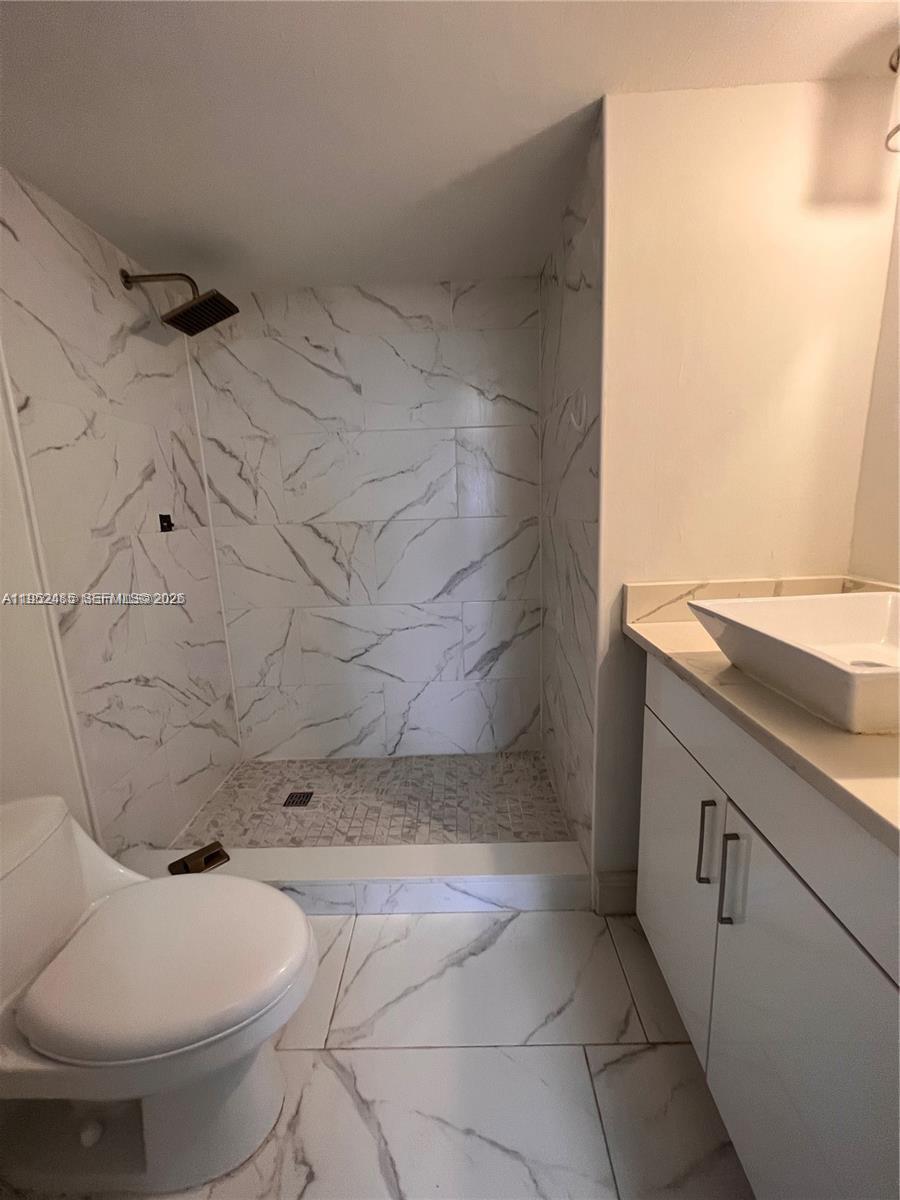 A bathroom features a walk-in shower with marble-look tile, a white vanity, and a toilet — 16220 NW 2nd Ave # 511, Miami FL 33169, MIAMI, FL