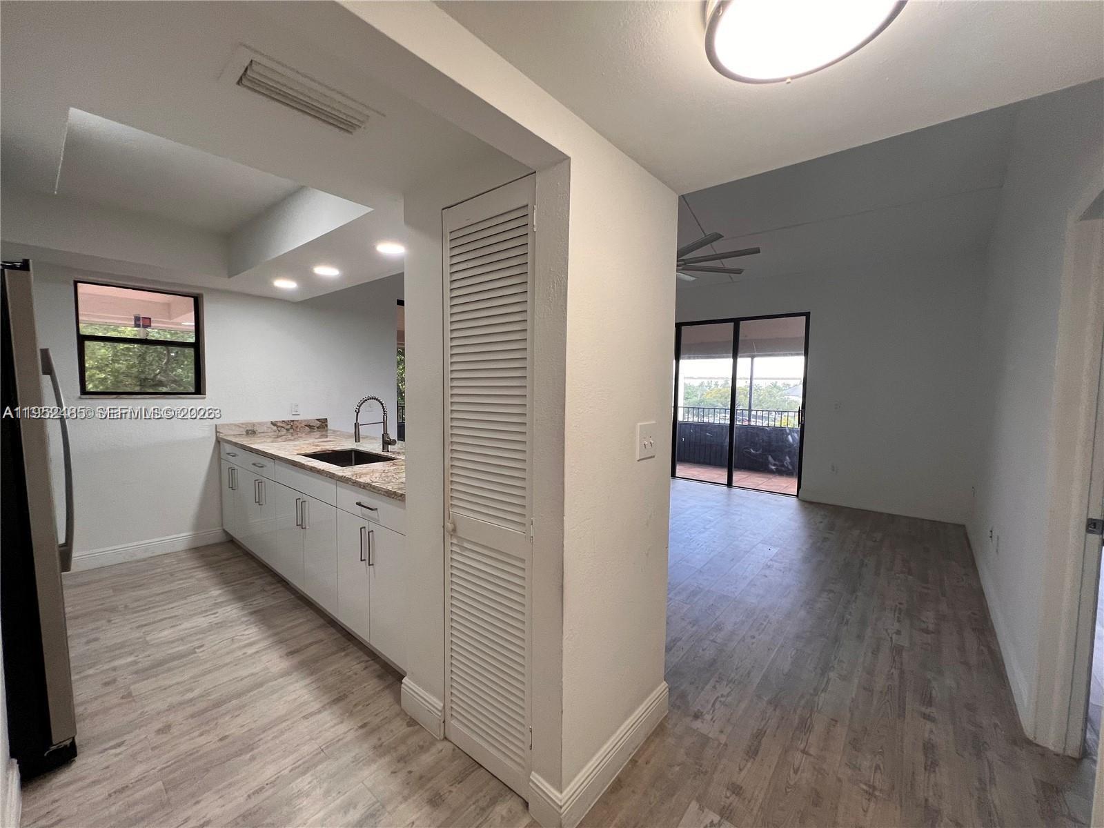 A kitchen with white cabinets and granite countertops opens into a living area with balcony access — 16220 NW 2nd Ave # 511, Miami FL 33169, MIAMI, FL