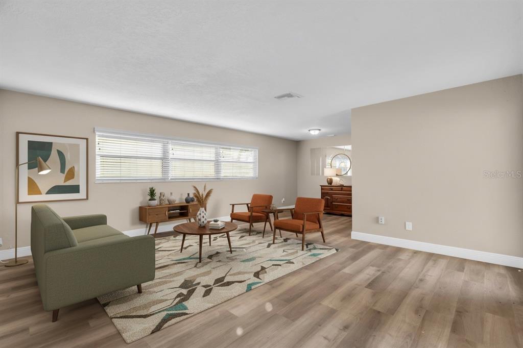 A living room features light wood-look flooring, a green sofa, and two orange armchairs — 6860 PARK STREET S, SOUTH PASADENA, FL