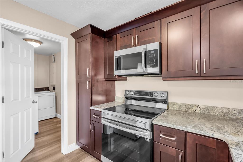 A kitchen features dark wood cabinets, stainless steel appliances, and granite countertops — 6860 PARK STREET S, SOUTH PASADENA, FL