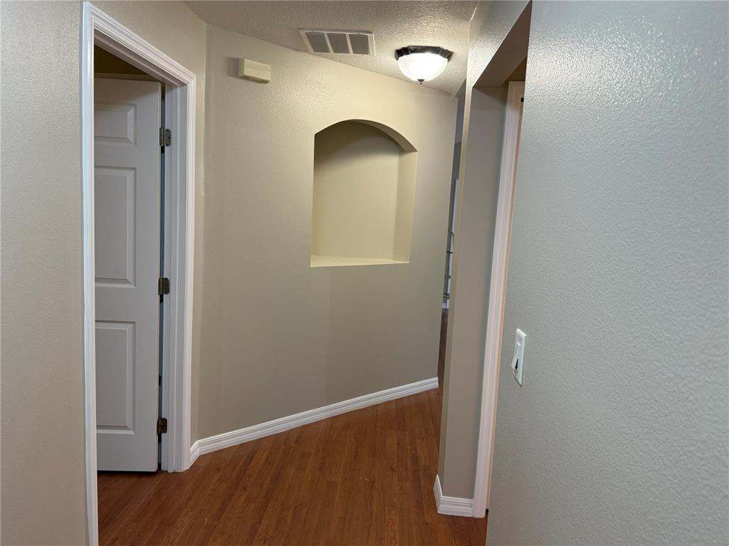A hallway features wood-look flooring, a recessed wall niche, and a ceiling light fixture — 731 SE 30TH AVENUE, OCALA, FL