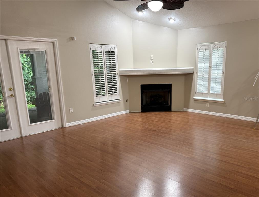 A living room features wood-look flooring, a corner fireplace with a mantel, and plantation shutters — 731 SE 30TH AVENUE, OCALA, FL