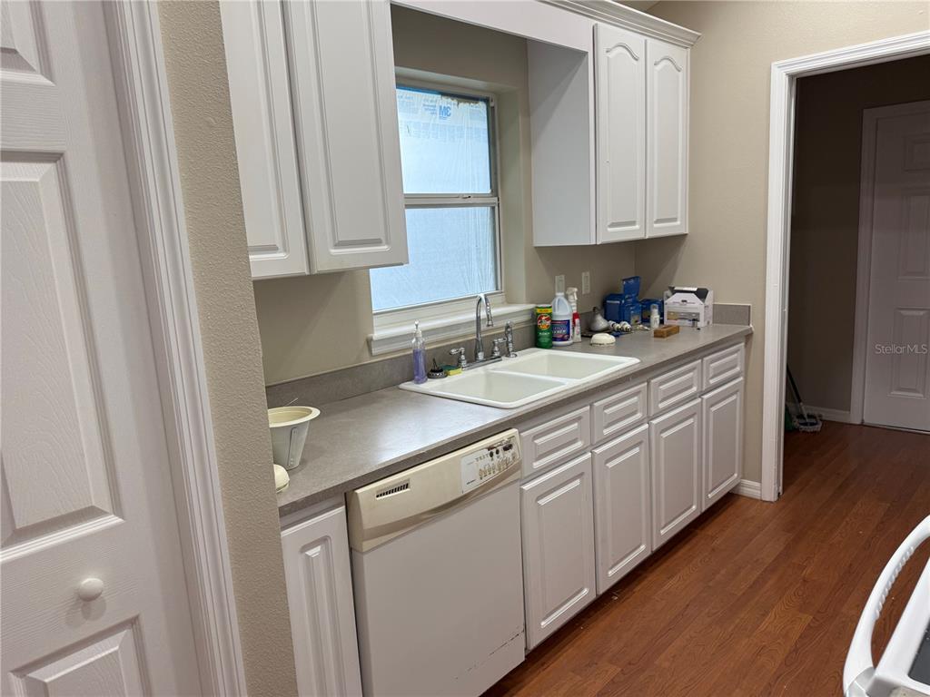 A kitchen features white cabinets, a double-basin sink, a dishwasher, and wood-look flooring — 731 SE 30TH AVENUE, OCALA, FL