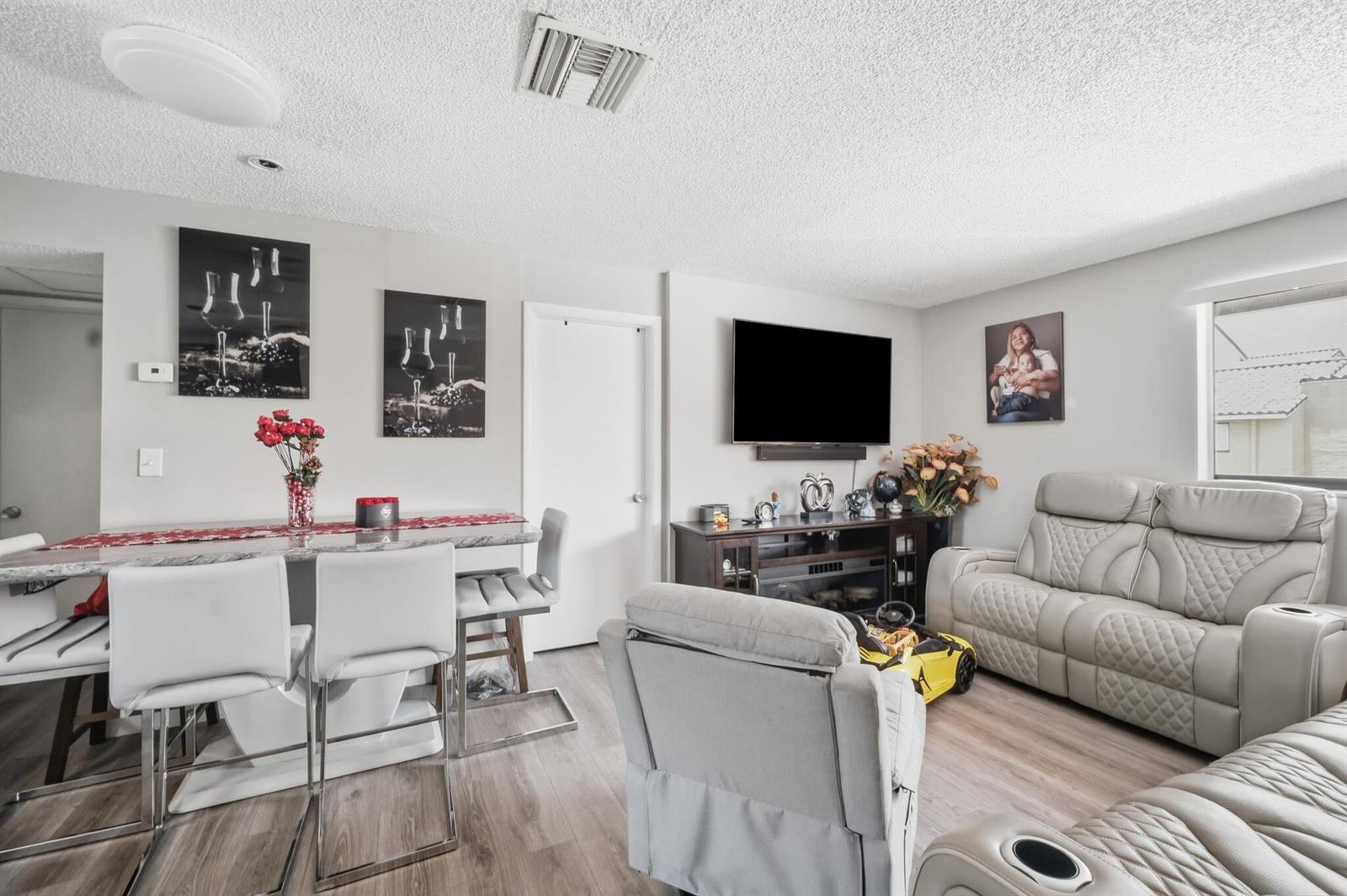 A living room and dining area feature light wood flooring, gray furniture, and white walls — 2710 W 60th Place # 205, Hialeah FL 33016, HIALEAH, FL