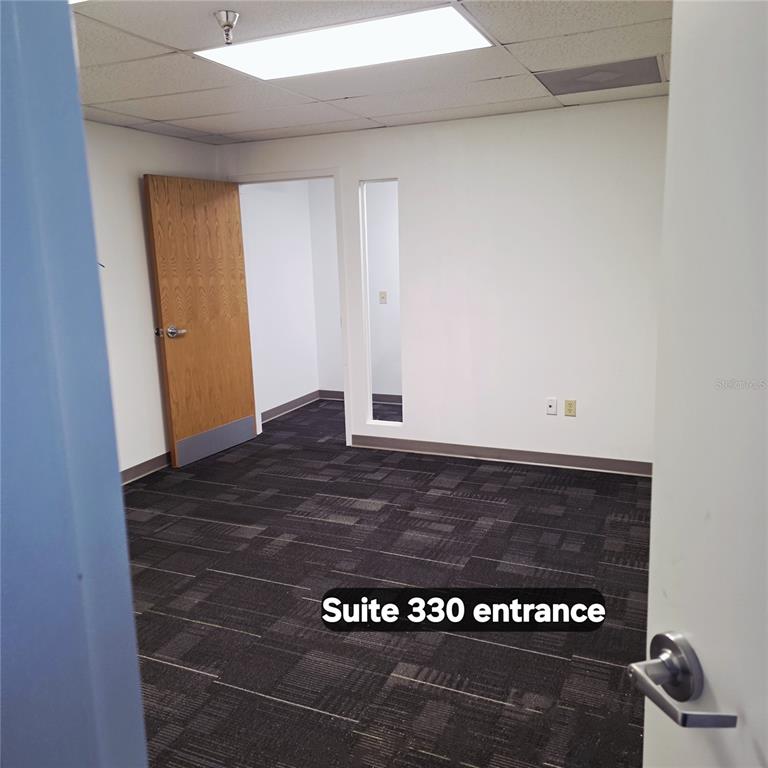 An office suite entrance features dark patterned carpet, white walls, and a wooden door — 29399 US HIGHWAY 19 N, CLEARWATER, FL