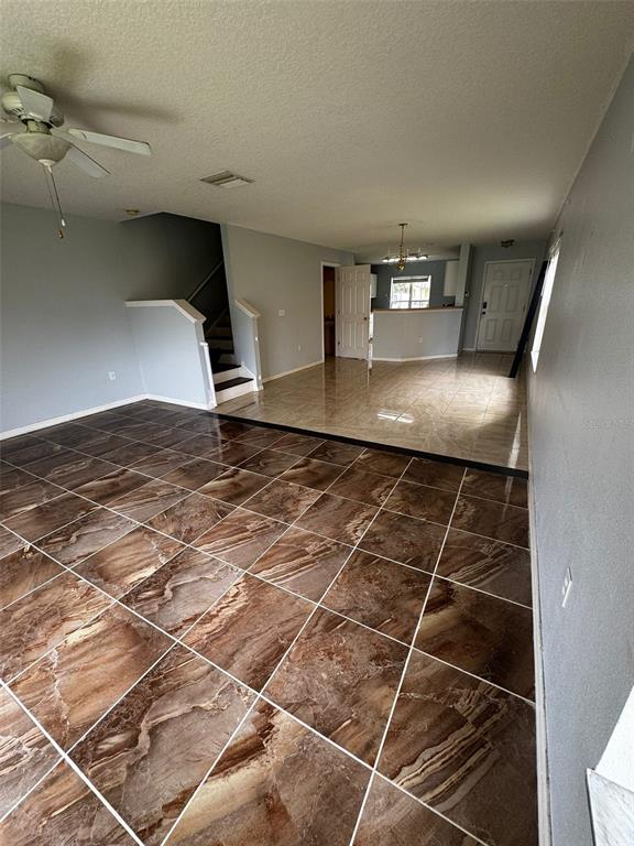 An interior view shows a living area with brown tiled floors transitioning to a kitchen area — 6913 MARBLE FAWN PLACE, RIVERVIEW, FL