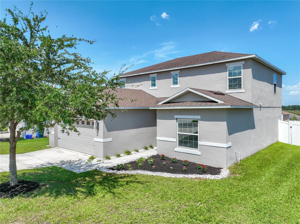 A two-story suburban house with a gray stucco exterior, a garage, and a front garden — 405 KESTREL DRIVE, GROVELAND, FL