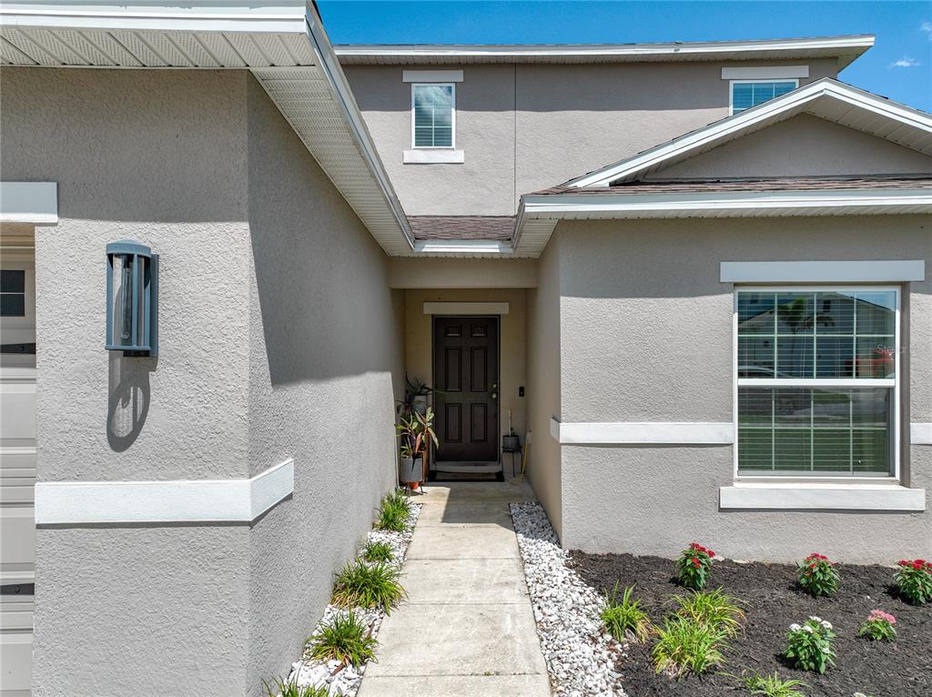 A concrete walkway leads to the front entrance of a two-story stucco house — 405 KESTREL DRIVE, GROVELAND, FL