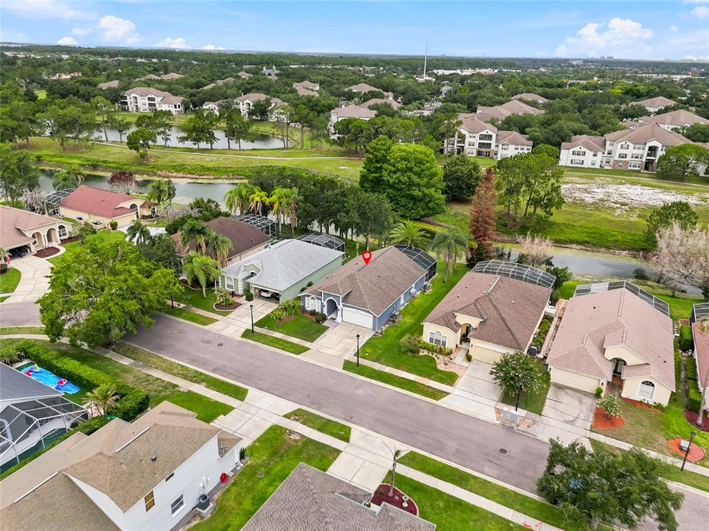 An aerial view shows a suburban neighborhood with houses, a pond, and green spaces — 2613 RUNYON CIRCLE, ORLANDO, FL