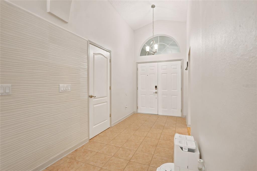 An entryway with tiled flooring, a textured accent wall, and a double front door — 2613 RUNYON CIRCLE, ORLANDO, FL
