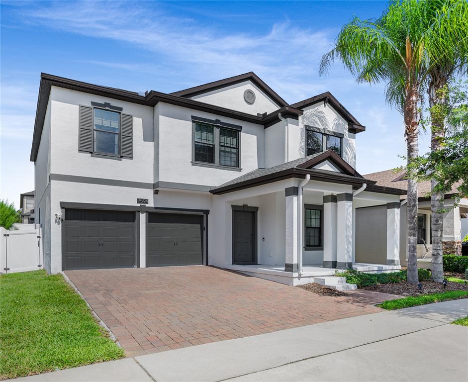 A two-story house with a white stucco exterior, dark trim, and a two-car garage — 7594 LAKE HANCOCK BOULEVARD, WINTER GARDEN, FL