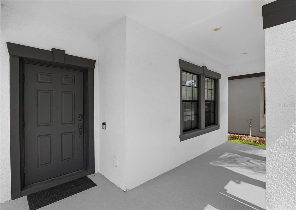 A covered entryway features a dark gray front door and a window with dark trim — 7594 LAKE HANCOCK BOULEVARD, WINTER GARDEN, FL