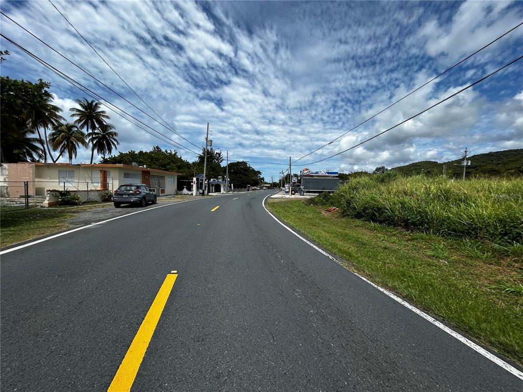 A paved road curves past a residential building and a small gas station — KM 115.8 PR-3 GUARDARRAYAS, PATILLAS, PR