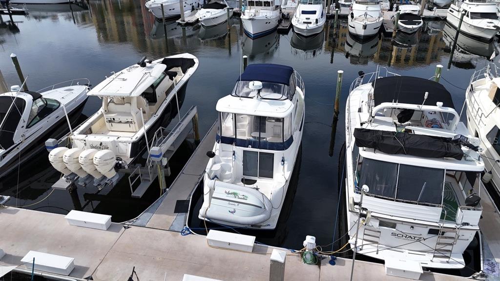 An aerial view shows three boats docked at a marina with several others in the background — 102 RIVIERA DUNES WAY UNIT S-72, PALMETTO, FL