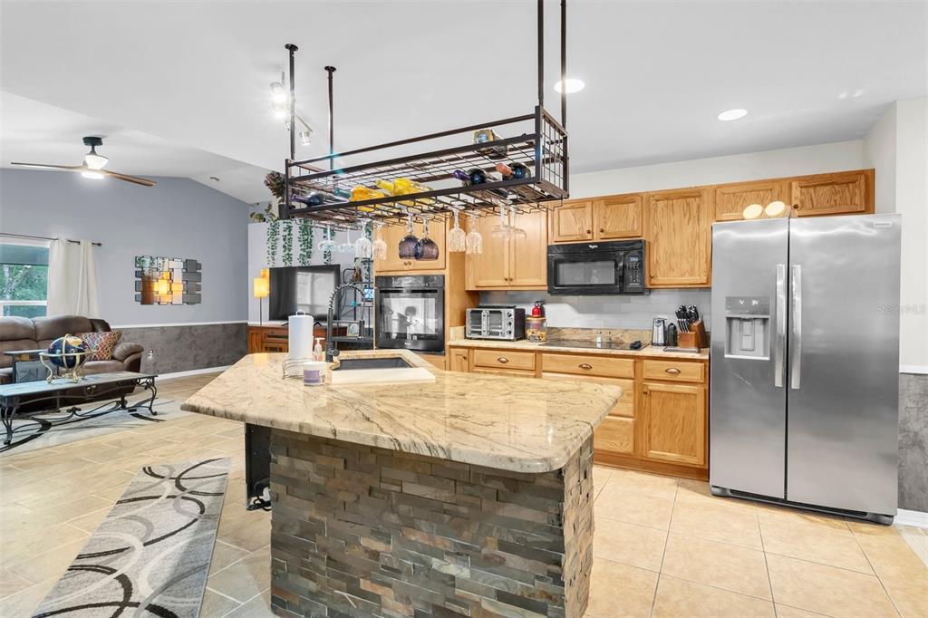 A kitchen with light wood cabinets, a stone-faced island, and a hanging wine glass rack — 11058 N MORRELL DRIVE, CITRUS SPRINGS, FL