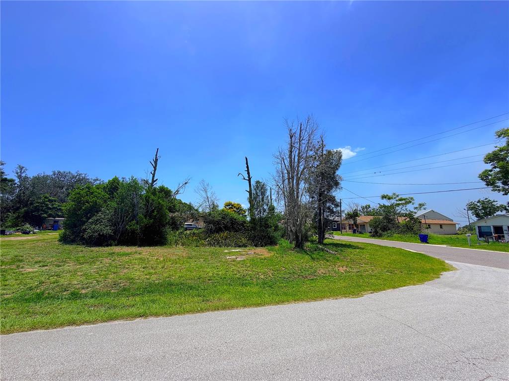 A grassy, partially wooded vacant lot sits at the corner of a paved road — 925 GRAND AVENUE, SEBRING, FL