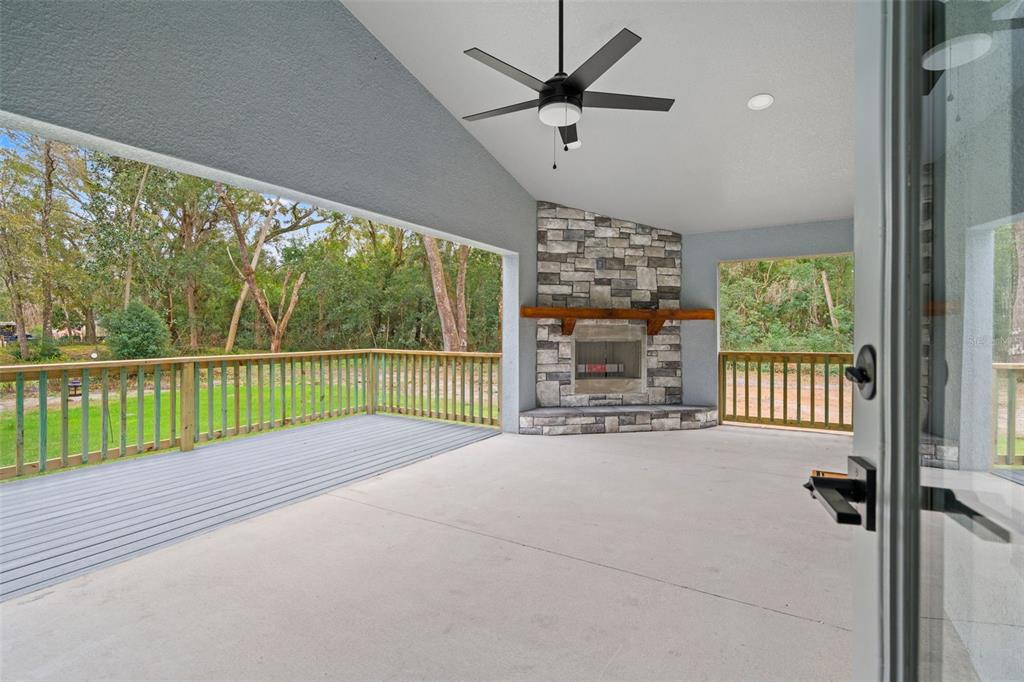 A covered patio features a stone fireplace, a ceiling fan, and a wooden deck — 478 LINCOLN AVENUE, BROOKSVILLE, FL
