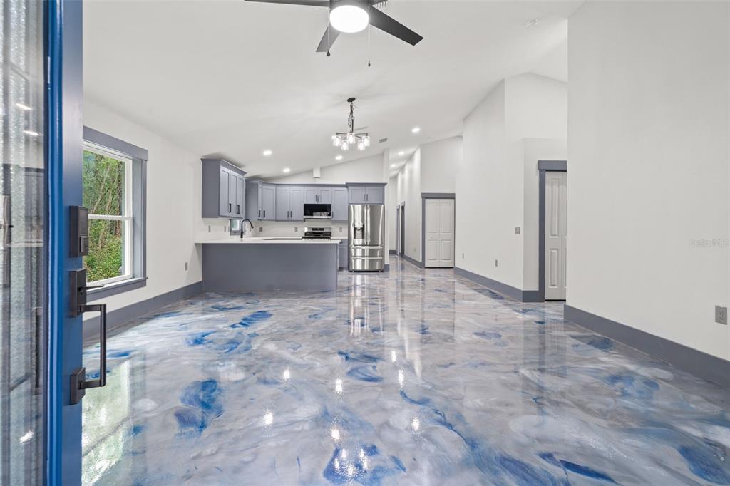 An open-concept kitchen and living area features blue-swirled epoxy flooring and gray cabinetry — 478 LINCOLN AVENUE, BROOKSVILLE, FL