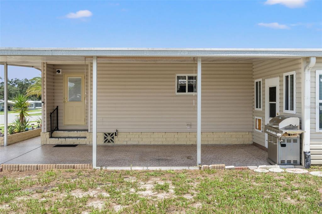 A covered patio with a concrete floor, beige siding, and a stainless steel grill — 8427 HIGHPOINT BOULEVARD, BROOKSVILLE, FL