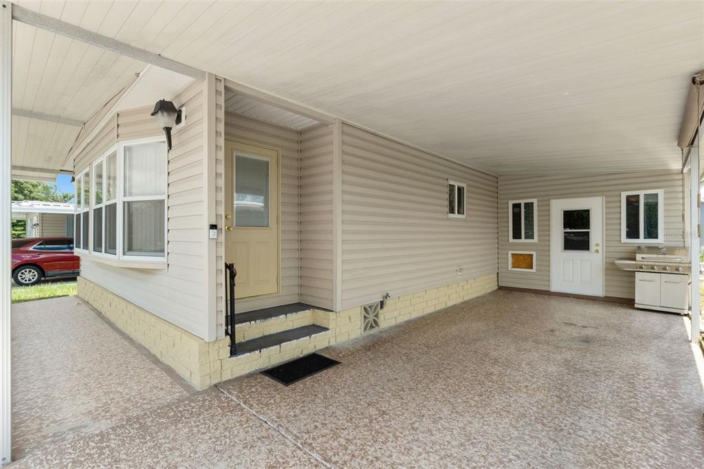 A covered carport area features a concrete floor, beige siding, and two exterior entry doors — 8427 HIGHPOINT BOULEVARD, BROOKSVILLE, FL