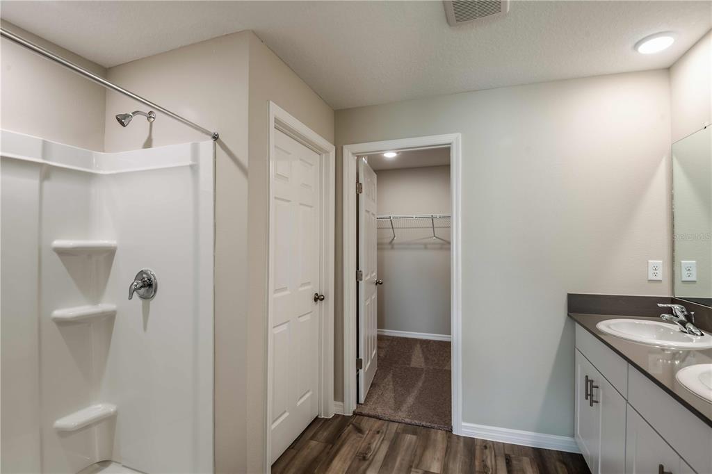A bathroom features a white shower stall, a vanity with a sink, and a walk-in closet — 4425 RIVERBEND BOULEVARD, HAINES CITY, FL