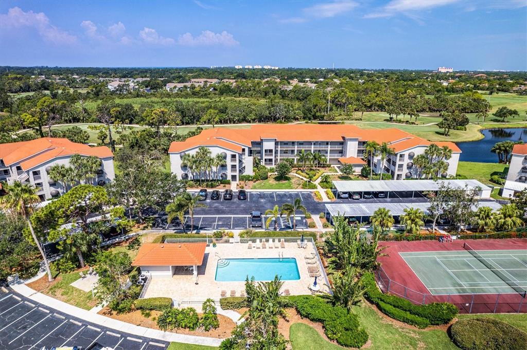 An aerial view of a multi-story apartment complex with a swimming pool and tennis court — 9320 CLUBSIDE CIRCLE UNIT 2108, SARASOTA, FL