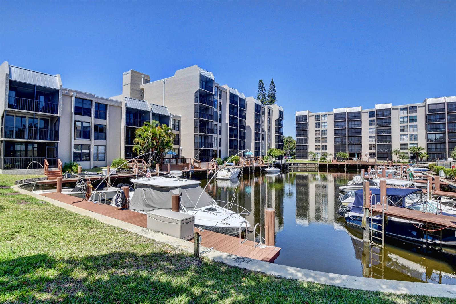 A canal with docked boats sits in front of multi-story apartment buildings under a clear sky — 4 Royal Palm Way # 308, Boca Raton FL 33432, BOCA RATON, FL