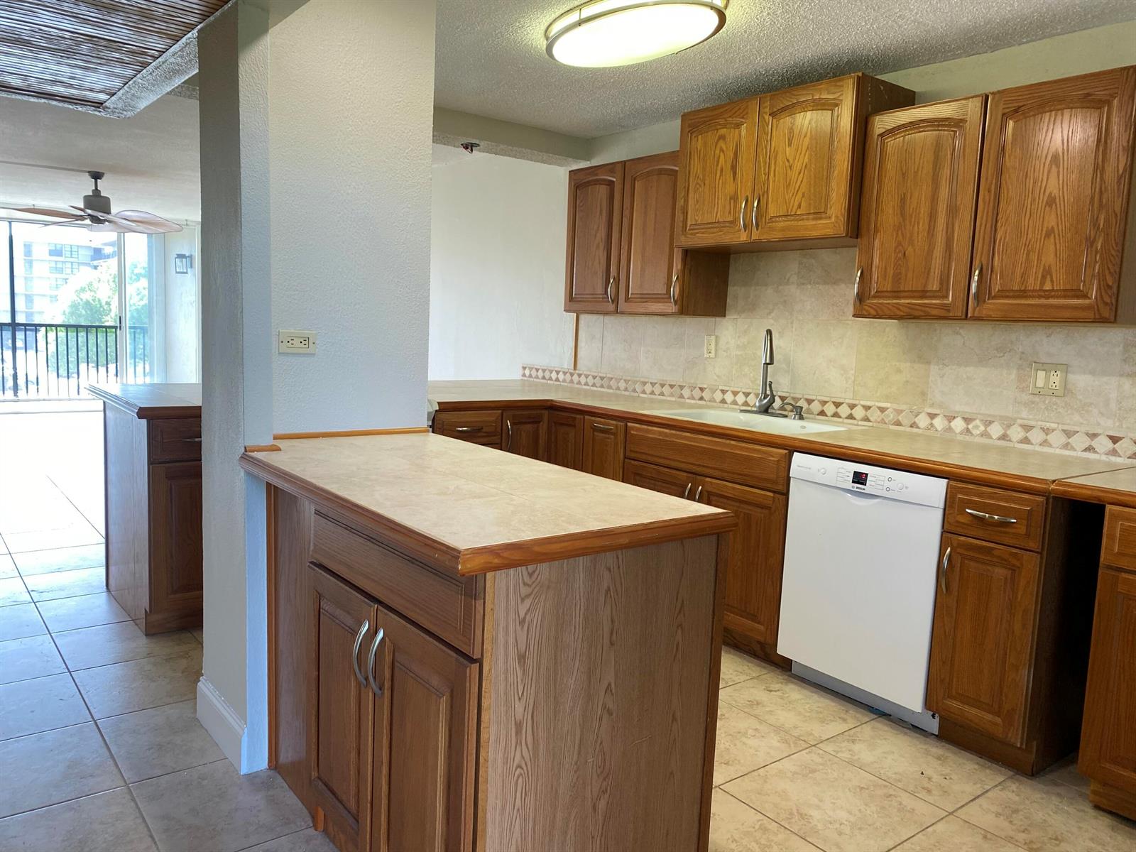 A kitchen features oak cabinets, tile countertops, a white dishwasher, and a tile floor — 4 Royal Palm Way # 308, Boca Raton FL 33432, BOCA RATON, FL