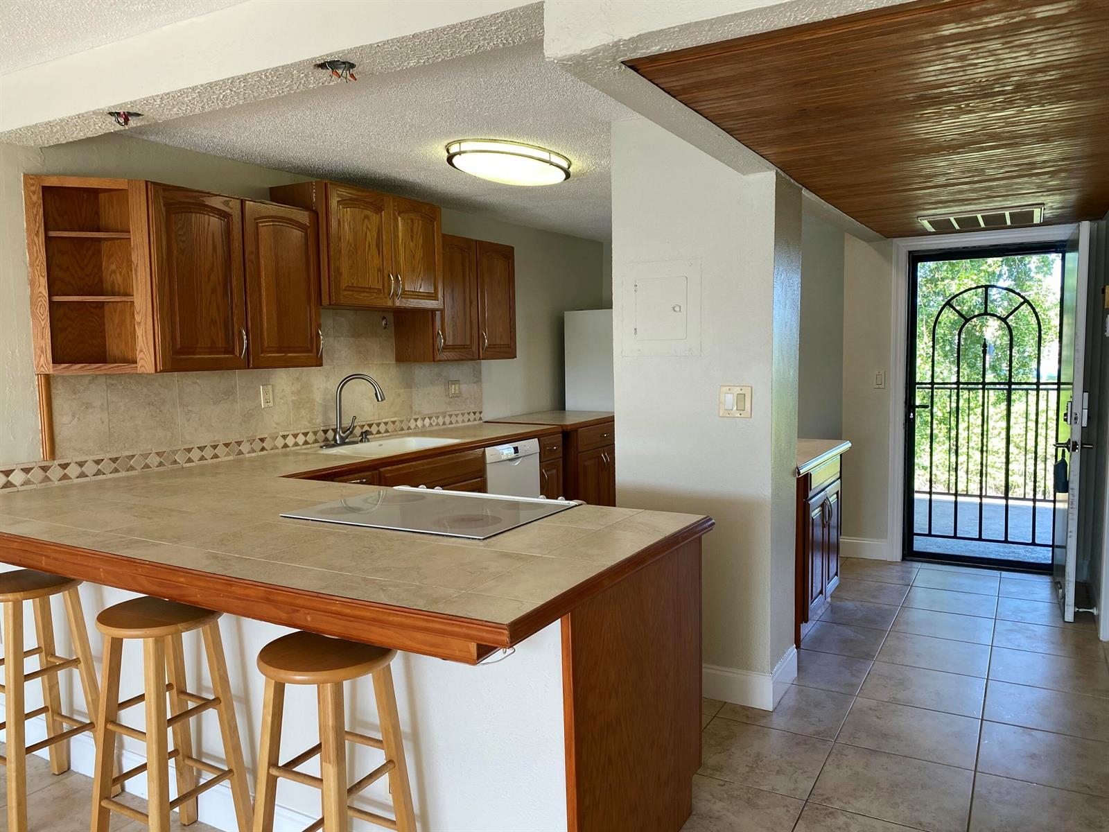 A kitchen features oak cabinets, tiled countertops, a breakfast bar, and a glass-paned exterior door — 4 Royal Palm Way # 308, Boca Raton FL 33432, BOCA RATON, FL