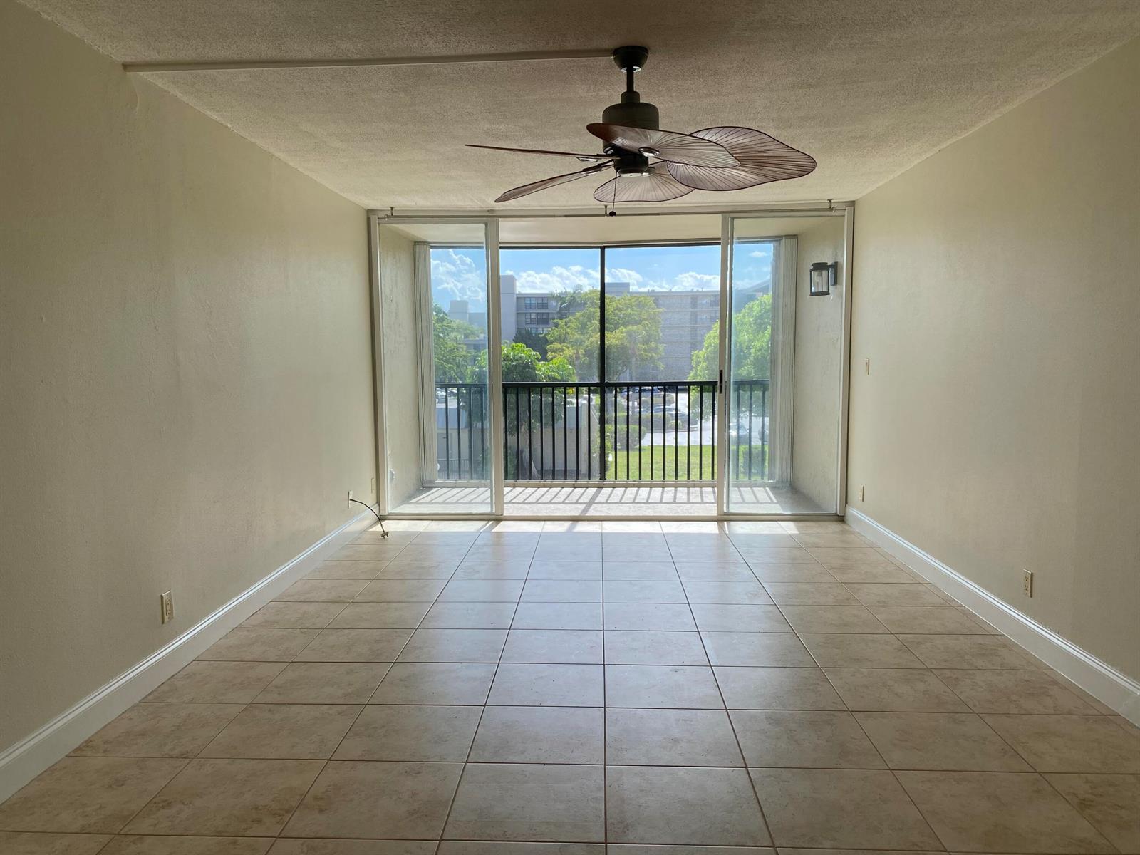 An empty room with beige tile flooring, a ceiling fan, and sliding glass doors to a balcony — 4 Royal Palm Way # 308, Boca Raton FL 33432, BOCA RATON, FL