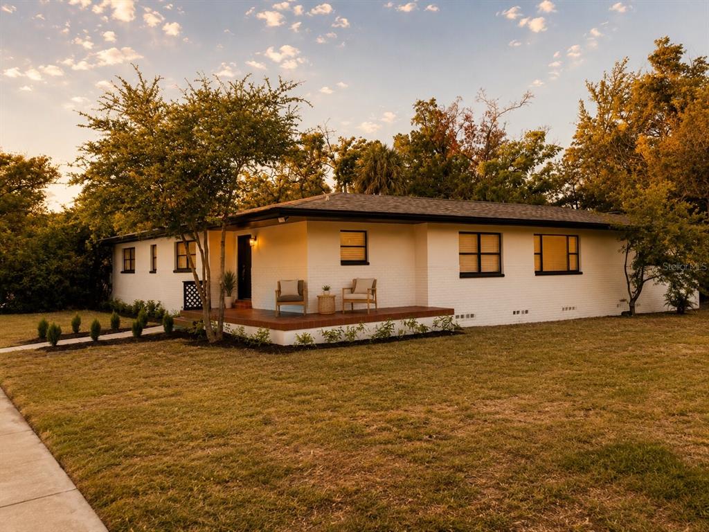 A single-story white brick house with a front porch and dark-framed windows at sunset — 2605 E 17TH AVENUE, TAMPA, FL