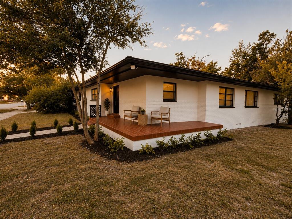 A white brick house with a dark roof and a tiled front porch at sunset — 2605 E 17TH AVENUE, TAMPA, FL