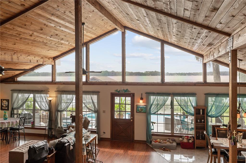 A living room with a vaulted wood-paneled ceiling, large windows, and a view of water — 285 LAKEVIEW DRIVE, TARPON SPRINGS, FL
