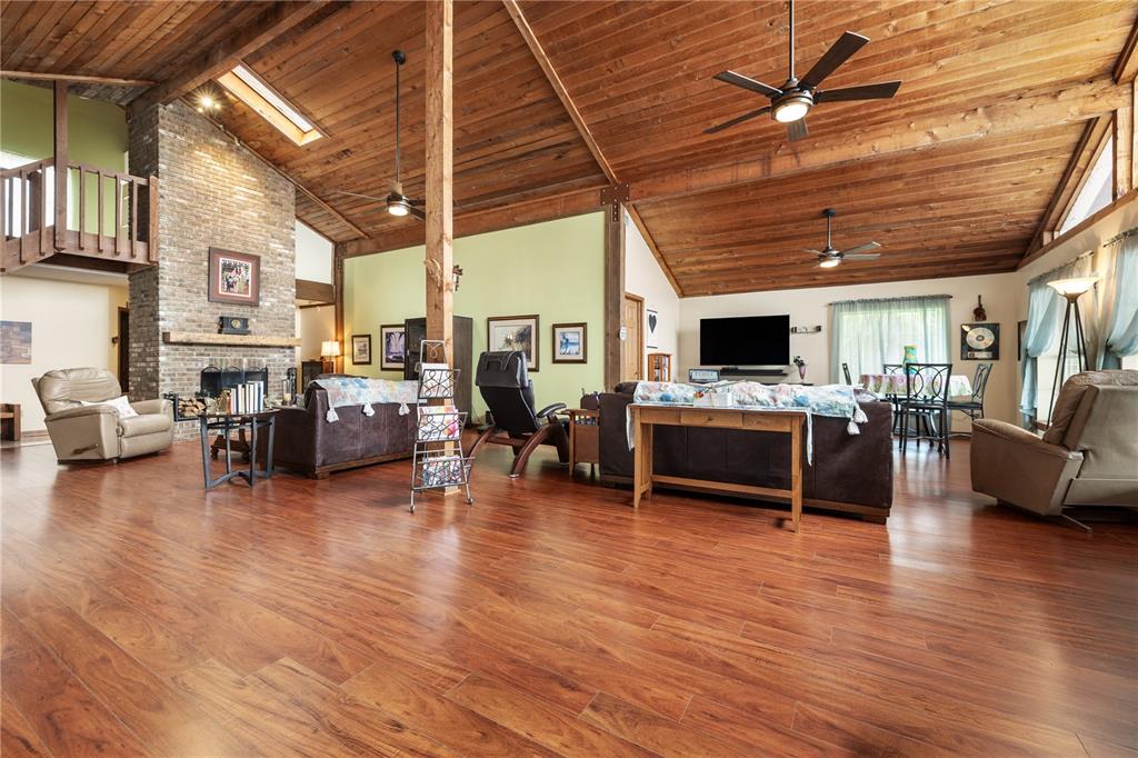 A spacious living room features a vaulted wood ceiling, brick fireplace, and hardwood flooring — 285 LAKEVIEW DRIVE, TARPON SPRINGS, FL