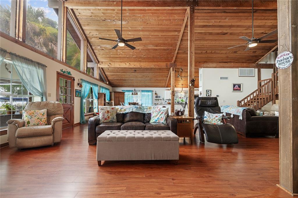 A living room features wood-plank ceilings, laminate flooring, and a large central leather sofa — 285 LAKEVIEW DRIVE, TARPON SPRINGS, FL