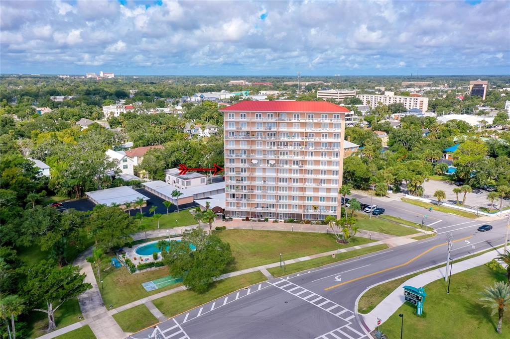 An aerial view shows a tall residential building with a red roof and a pool — 404 S BEACH STREET UNIT 230 (604), DAYTONA BEACH, FL