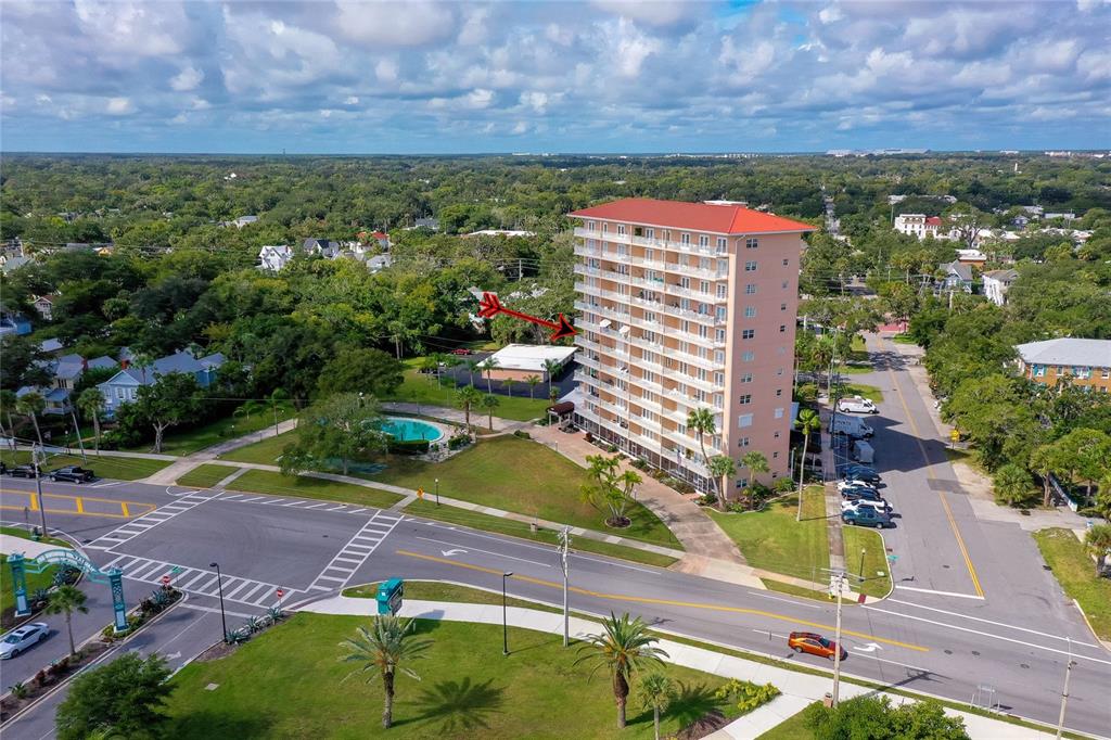 An aerial view shows a tall residential building with a red roof near a road — 404 S BEACH STREET UNIT 230 (604), DAYTONA BEACH, FL