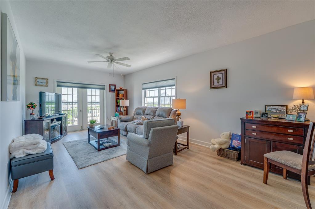 A living room features light wood-look flooring, a gray sofa, an armchair, and a balcony door — 404 S BEACH STREET UNIT 230 (604), DAYTONA BEACH, FL