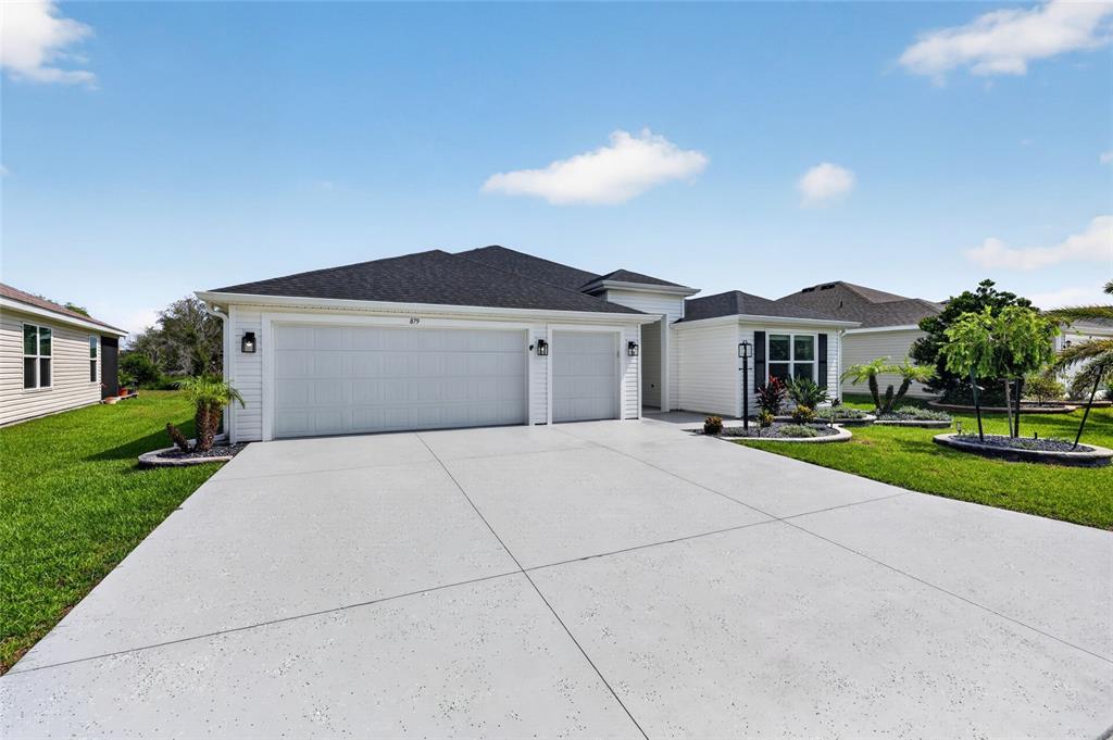 A white single-story house with a three-car garage and a concrete driveway — 879 MORLEY AVENUE, THE VILLAGES, FL
