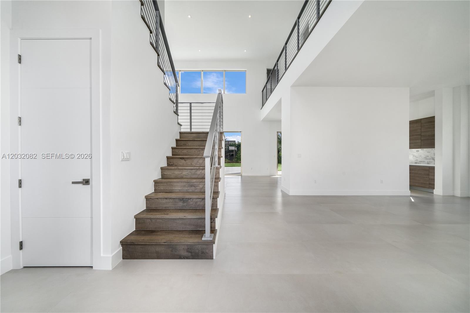 A modern interior features a wooden staircase, white walls, and large gray floor tiles — 16720 N Botaniko Dr N, Weston FL 33326, WESTON, FL