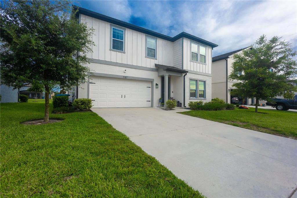 A two-story house with a white exterior, a two-car garage, and a concrete driveway — 1187 PEARL TREE ROAD, DELTONA, FL