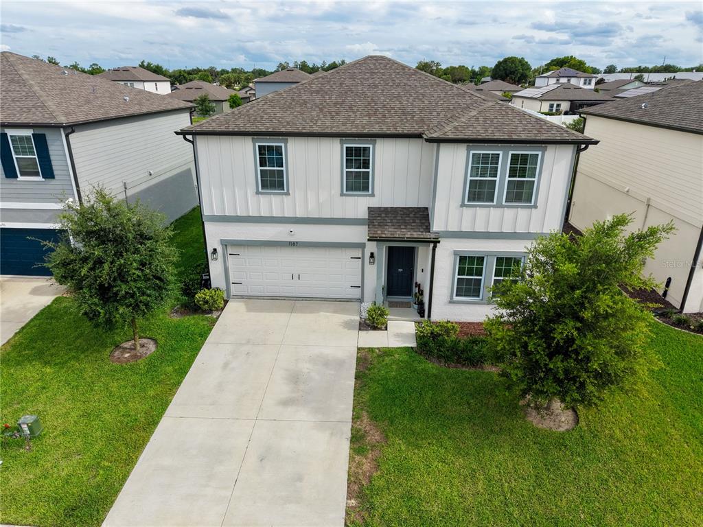 An aerial view of a two-story suburban house with a white exterior and concrete driveway — 1187 PEARL TREE ROAD, DELTONA, FL
