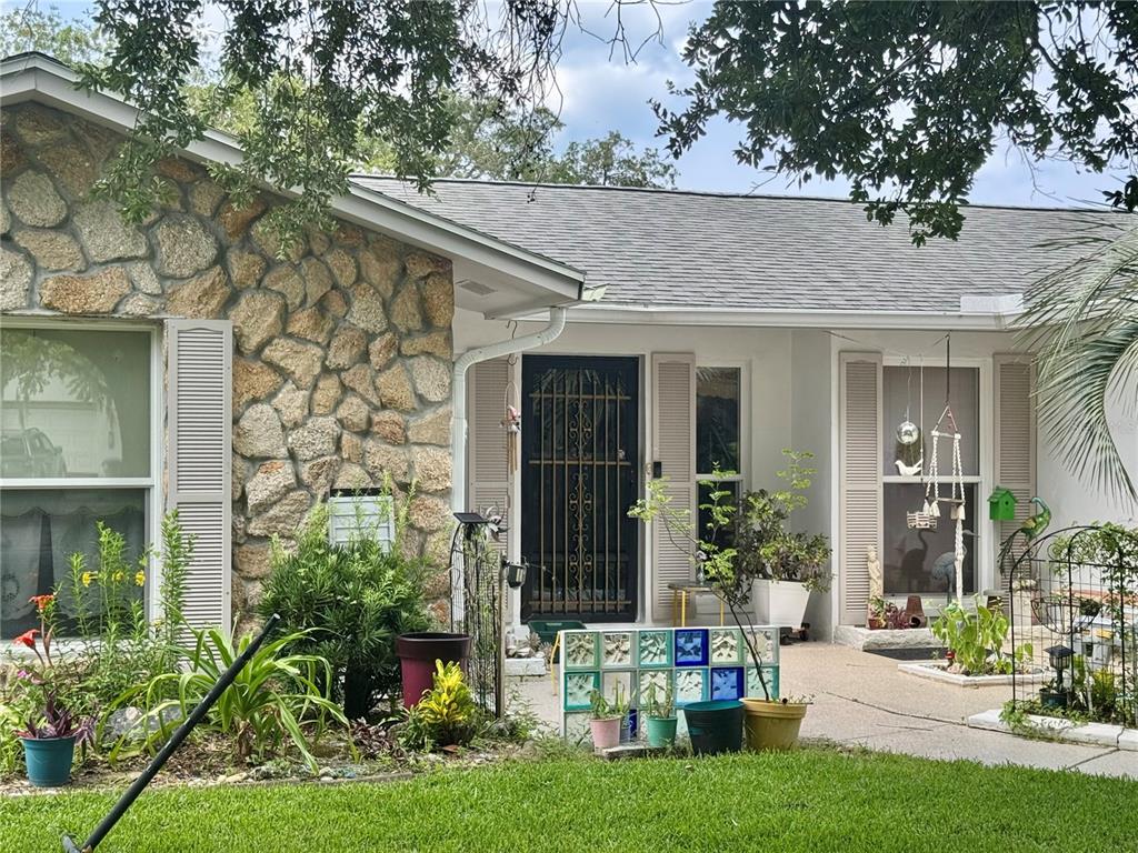 A single-story house exterior features a stone facade, a black security door, and potted plants — 30 FERNHAM LANE, PALM COAST, FL