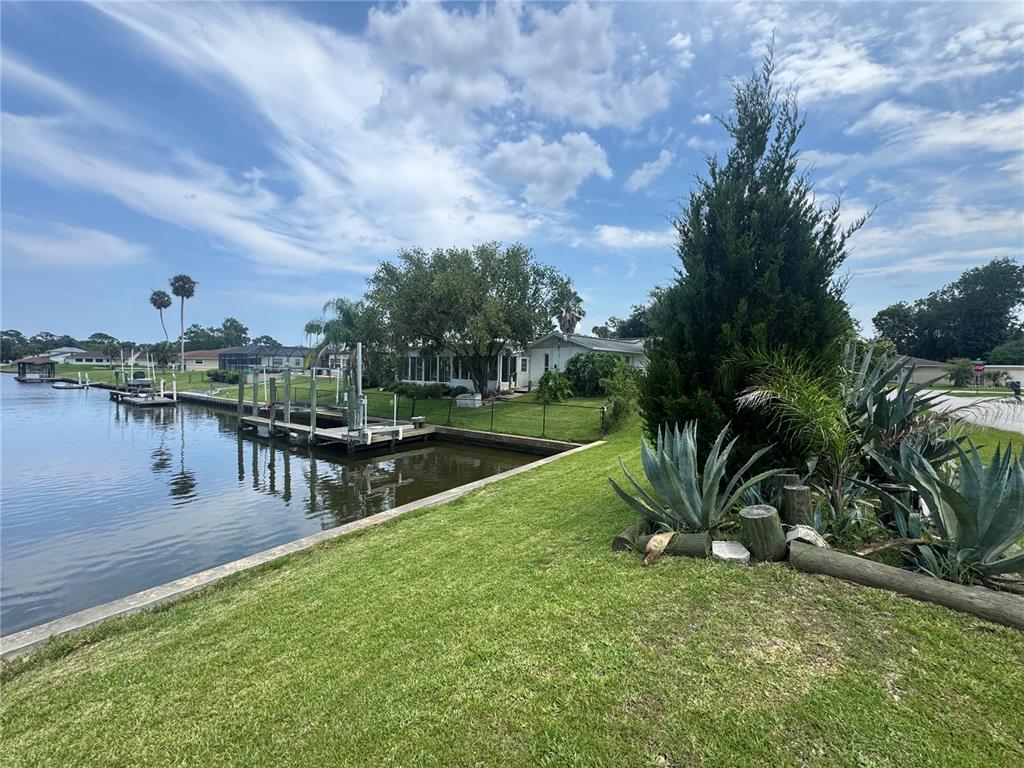 A waterfront property featuring a boat dock, a grassy lawn, and a small house — 30 FERNHAM LANE, PALM COAST, FL