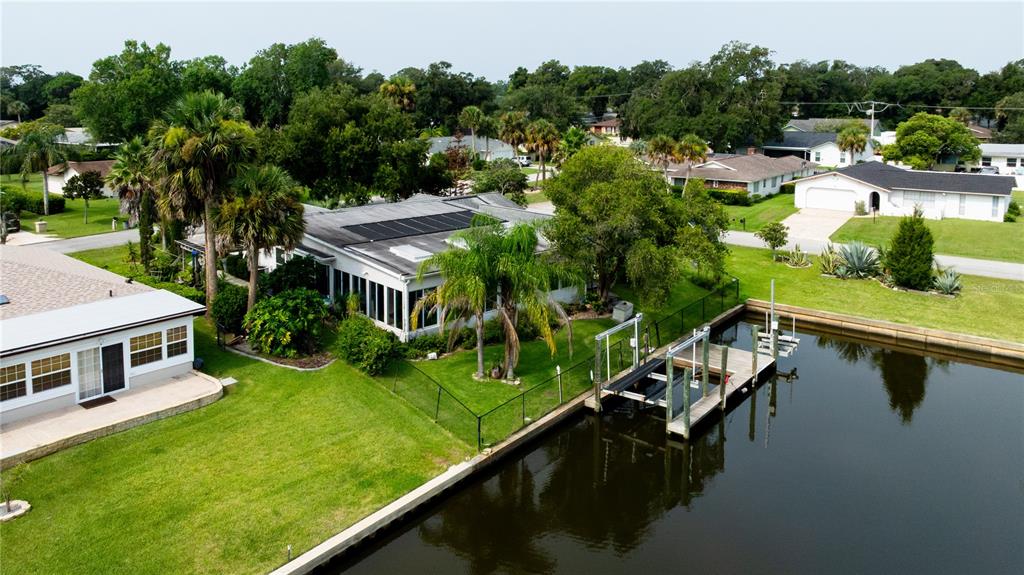 An aerial view shows a waterfront house with a boat dock and solar panels — 30 FERNHAM LANE, PALM COAST, FL