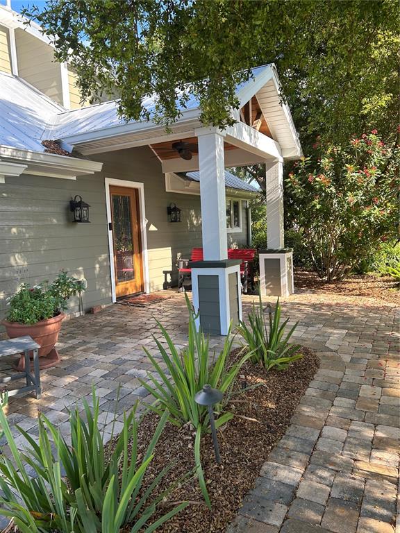 A covered porch with a wooden door, stone pavers, and a white columned entryway — 614 RAVENNA STREET, VENICE, FL