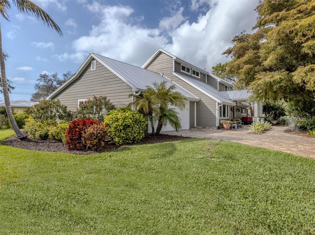 A two-story house with gray siding, a metal roof, and a paved driveway — 614 RAVENNA STREET, VENICE, FL