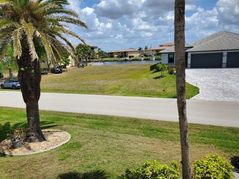 An exterior view shows a vacant lot between two houses with a canal in the background — 3233 WOOD THRUSH DRIVE UNIT 24A, PUNTA GORDA, FL
