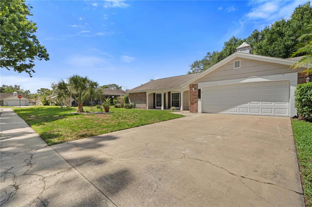 A single-story house with a beige exterior, a two-car garage, and a concrete driveway — 8702 POWDERHORN ROW, HUDSON, FL